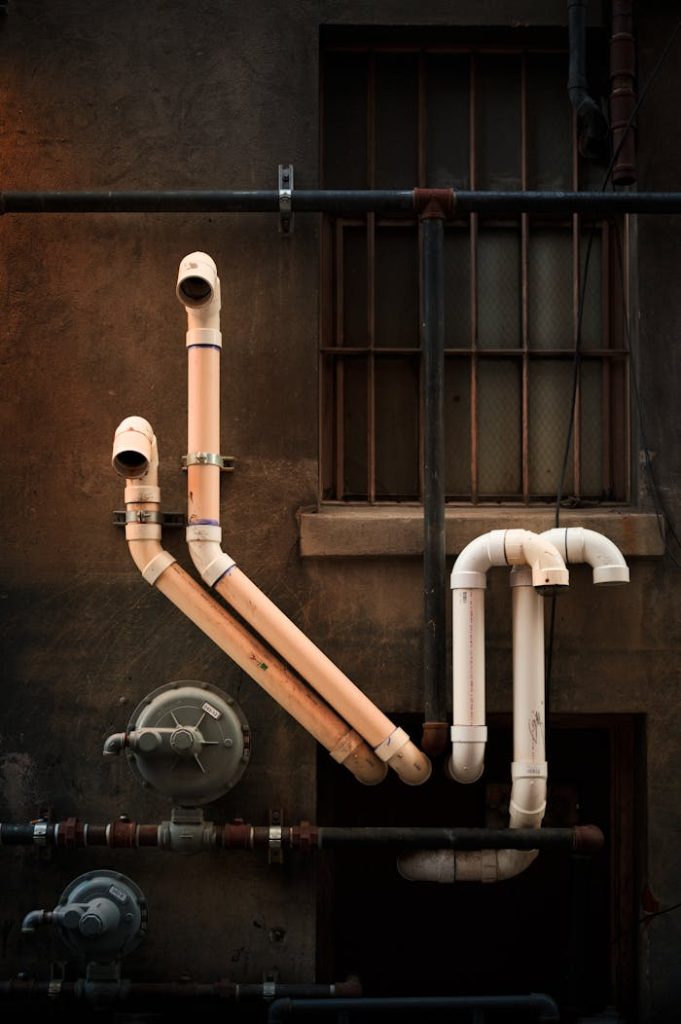 pexels photo 12778827 Vertical shot of industrial pipes on urban building wall, showcasing intricate installation.