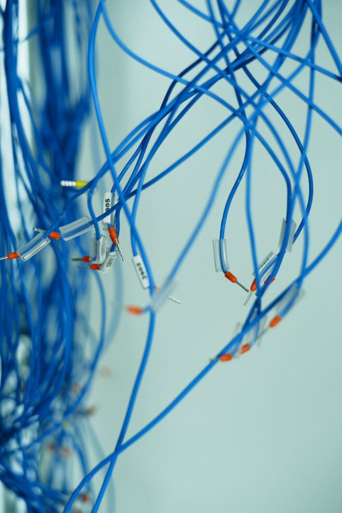pexels photo 15559030 Close-up of tangled blue wires with connectors on a white background, emphasizing connection.