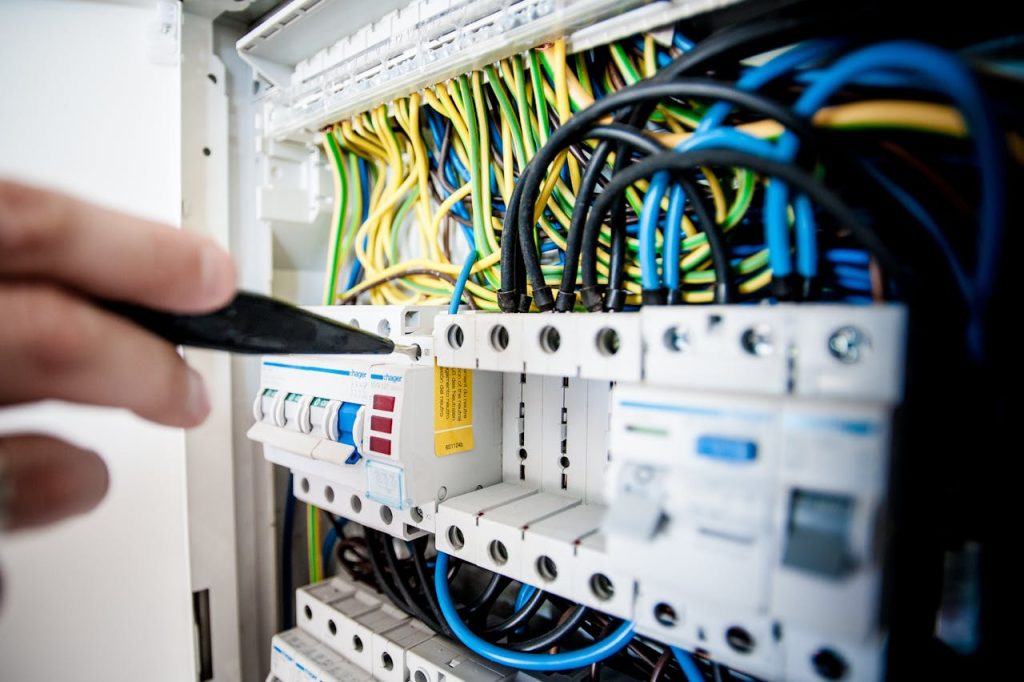 pexels photo 257736 Hand of electrician working on a circuit breaker panel with colorful wires, ensuring safe electrical connections.